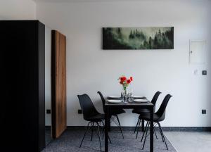 a dining room table with black chairs and a vase of flowers at Pokoje Na Winklu in Kluszkowce