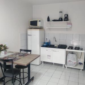 a small kitchen with a table and a microwave at Apto 03 - 1 quarto com 2 camas solteiro e garagem, possui ventilador de teto in Cascavel