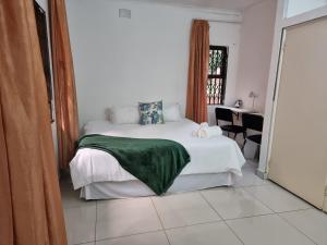 a bedroom with a bed with a green blanket on it at 56 Archer Crescent Mainhouse in Durban