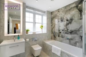 a bathroom with a tub and a toilet and a sink at BRAND NEW Spacious 4 Bedroom Houses For Contractors & Families with FREE Parking, Garden, Fast Wifi and Netflix By REDWOOD STAYS in Farnborough
