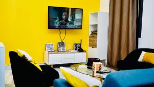 a living room with yellow walls and a table and chairs at Grand Appartement LUXE secteur Mamelles et Monument de la renaissance in Ouakam