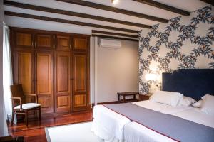 a bedroom with a large bed and a chair at Hotel A Casa Do Rio in Padrón