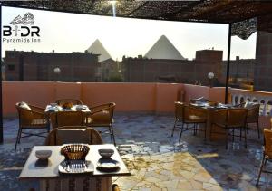 eine Terrasse mit Tischen und Stühlen auf dem Dach in der Unterkunft King Badr pyramids in Kairo