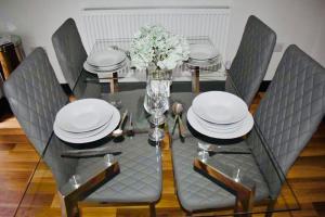 a dining table with plates and a vase of flowers at Beeston House 3 BR and FREE Parking in Beeston