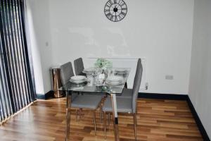 a dining room table with chairs and a clock on the wall at Beeston House 3 BR and FREE Parking in Beeston