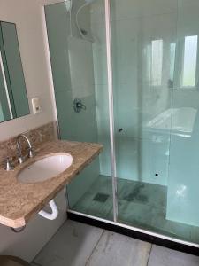 a bathroom with a sink and a glass shower at Apartamento Praia da Cal in Torres
