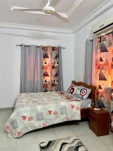 a bedroom with a bed with a comforter and a mask at Appartement hôte + in Ouagadougou