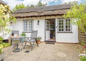 a small white cottage with a thatched roof at Half Moon Cottage in West Runton