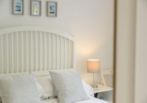 ein Schlafzimmer mit einem weißen Bett und einem Tisch mit einer Lampe in der Unterkunft Half Moon Cottage in West Runton