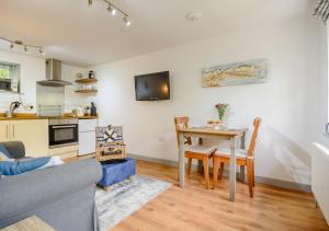 a living room with a table and a kitchen at Half Moon Cottage in West Runton