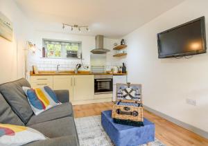 a living room with a couch and a tv on the wall at Half Moon Cottage in West Runton