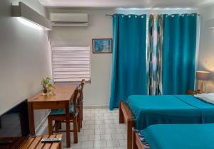 a room with two beds and a table and a blue curtain at Salines Studios in Sainte-Anne