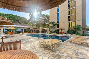 une piscine avec des bancs et un bâtiment dans l'établissement Mahana 804, à Kahana