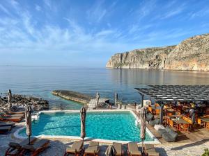 uma piscina junto ao oceano com cadeiras em Kyrimai Hotel em Yerolimin