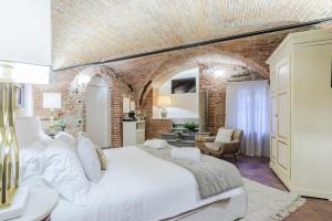 a bedroom with a white bed and a brick wall at Lucca Heritage Retreat in Lucca