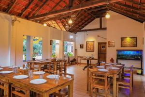 comedor con mesas y sillas de madera en Dhanagiri Home Stay en Vythiri