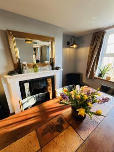 ein Wohnzimmer mit einem Holztisch mit Blumen darauf in der Unterkunft 3 bedroom Quirky Luxurious Cottage With Hot Tub in Heathfield