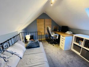 ein Schlafzimmer mit einem Bett und einem Schreibtisch im Dachgeschoss in der Unterkunft 3 bedroom Quirky Luxurious Cottage With Hot Tub in Heathfield