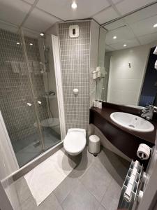 a bathroom with a toilet and a shower and a sink at Parc Hôtel in Carvin