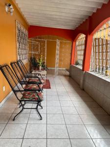eine Reihe von Stühlen auf einer Veranda mit orangefarbenen Wänden in der Unterkunft Casa Edgar in Manaus
