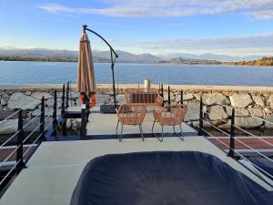 un patio con mesa, sillas y sombrilla en Floating Experience Black Pearl, Lago Maggiore en Dormelletto
