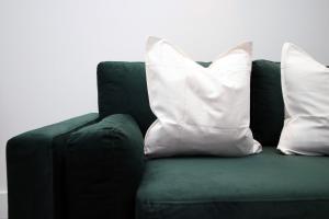 a green couch with two white pillows on it at 2 BR with Free Parking in Swindon