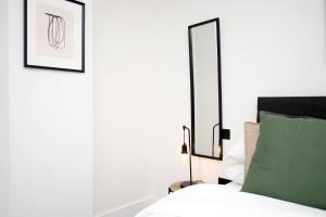 a bedroom with a bed with two mirrors on the wall at 2 BR with Free Parking in Swindon