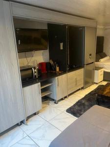 a room with a kitchen with a large tv at An elegant stay away from home in Johannesburg