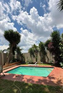 a swimming pool with palm trees in a yard at An elegant stay away from home in Johannesburg