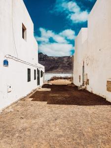 an alley way between two white buildings with mountains in the background at Casa Rosa in Famara