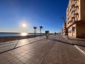 an empty sidewalk next to a beach with palm trees at Amplio con Patio y vistas a la Plaza in Dolores