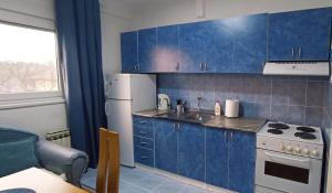 a kitchen with blue cabinets and a white refrigerator at Apartment White Angel in Kostolac +3 photos