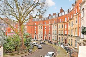 uma rua com carros estacionados em frente aos edifícios em Renovu Premium Homes in Kensington em Londres