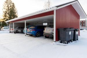 a garage with two cars parked in the snow at Rivitalokaksio *Autokatospaikka* in Seinäjoki