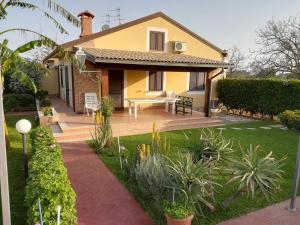 拉斯卡里的住宿－Villa Mimmo，庭院里设有木甲板的黄色房子