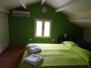 a green bedroom with a bed with two towels on it at Villa Mimmo in Lascari