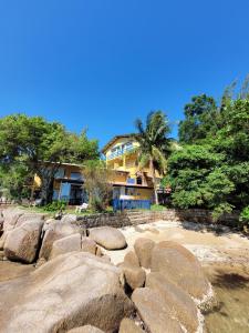 un edificio en una playa con rocas grandes en Prainha da Nina Apartamentos, en Florianópolis