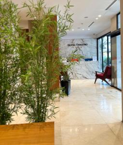 a lobby with potted plants in a building at Hotel Theatro- City Center in Tirana