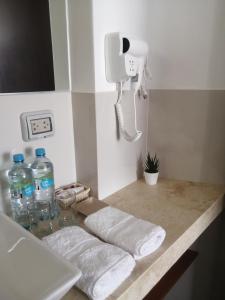 a bathroom counter with towels and a phone and water bottles at Casa Yuraq Hotel Boutique in Chincha Alta