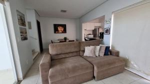 Il comprend un salon avec un canapé brun et une cuisine. dans l'établissement Apartamento Confortável e Espaçoso, à Sinop