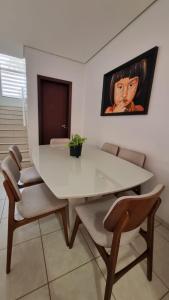 a dining room with a white table and chairs at Apartamento Confortável e Espaçoso in Sinop