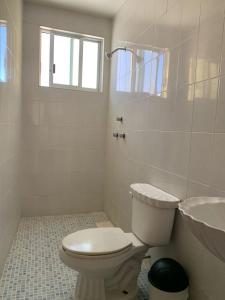 a white bathroom with a toilet and a sink at Hotel Renacimiento in Comitán de Domínguez