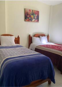 two beds in a room with a painting on the wall at Hotel Renacimiento in Comitán de Domínguez