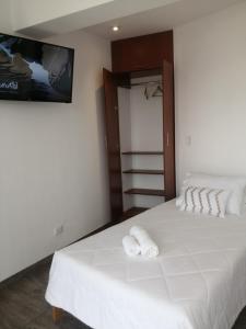 a bedroom with a white bed with two towels on it at Casa Yuraq Hotel Boutique in Chincha Alta