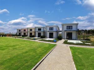 a row of white houses with a green lawn at Aurora Suites in Nea Fokea