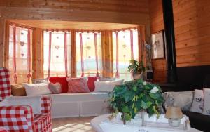 a living room with a couch in front of windows at Carmeta - Casa Rural de madera con jardín, piscina privada y barbacoa - Deltavacaciones in L'Eucaliptus