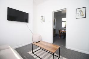 a living room with a table and a tv on a wall at Bristol Street 2 BR FREE onsteet parking in Newport