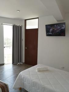 1 dormitorio con 1 cama y TV en la pared en Casa Yuraq Hotel Boutique, en Chincha Alta