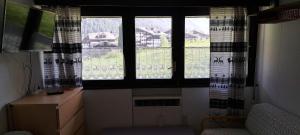 Habitación con 3 ventanas grandes en una habitación con escritorio. en La Thuile bilocale frazione Entrèves Condominio Ametista 30, en La Thuile