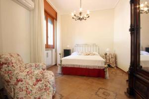 a bedroom with a bed and a chair and a chandelier at Casa Vacanze Catalano in Erice